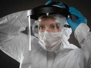 Woman wearing protective gear, including face mask, googles, gloves, and face shield