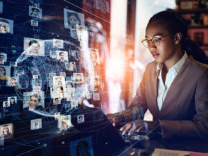 Black professional woman at a computer with an overlay graphic suggesting global communications technology