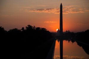 silhouettes of the Washington Monument and US Capitol against a sunset