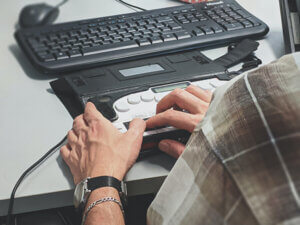closeup of person using assistive device with computer keyboard
