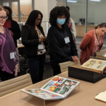 candid photo of six fellows looking at a few books from Special Collections