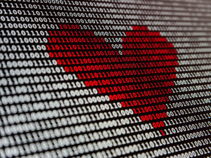 red heart superimposed on black-and-white screen of zeros and ones