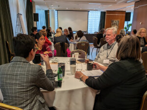 candid photo of ILP Fellows seated in small groups at round tables in a meeting room