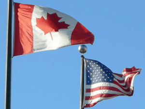 national flags of Canada and the United States waving in the wind side-by-side