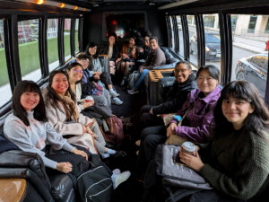 12 adults seated on a bus, smiling for the photo