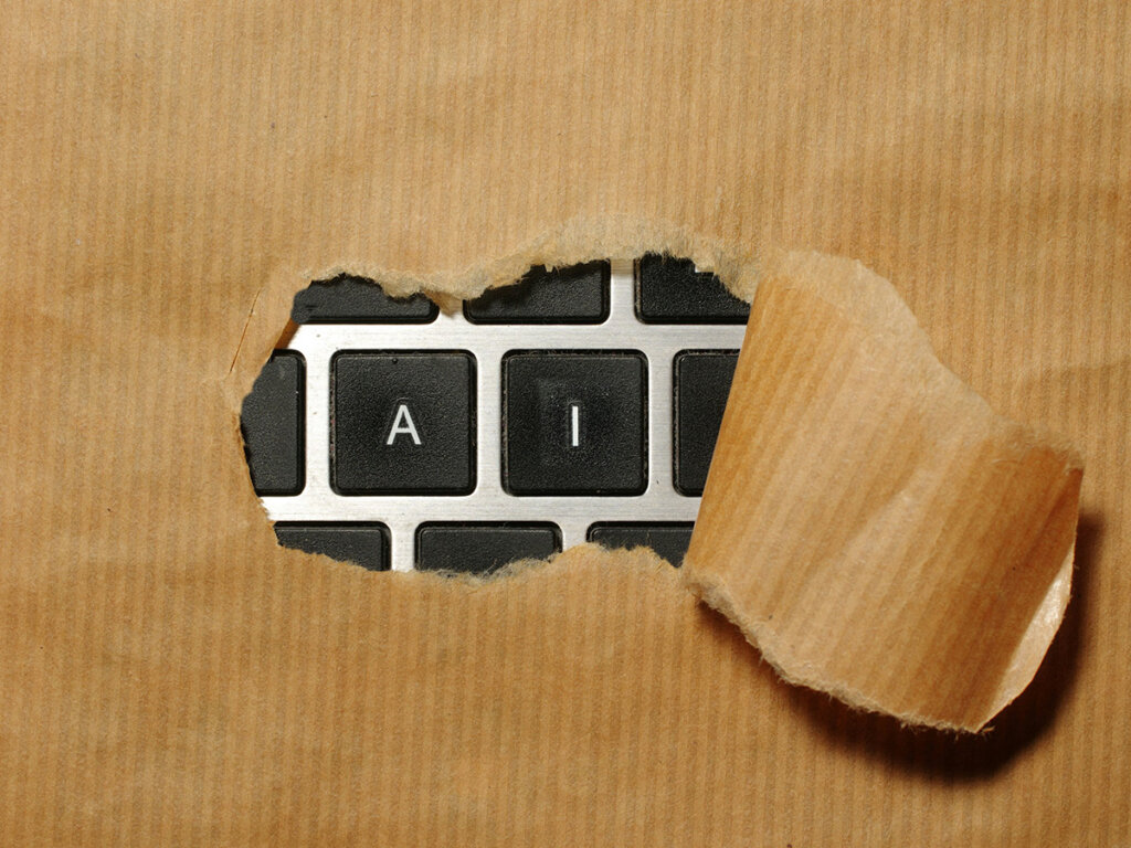 laptop keyboard buttons for "a" and "i" revealed by torn brown paper pulled away from where the paper covers the rest of the keyboard